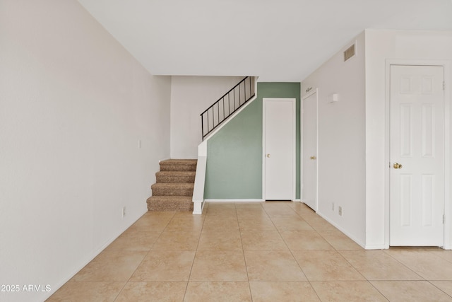 entrance foyer with light tile patterned floors, stairs, and baseboards