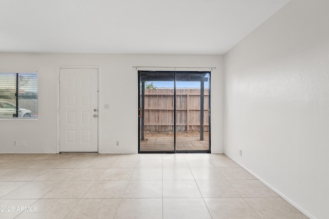 tiled empty room featuring healthy amount of natural light and baseboards