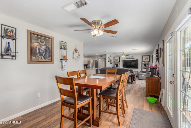 dining room featuring a ceiling fan, baseboards, visible vents, and wood finished floors