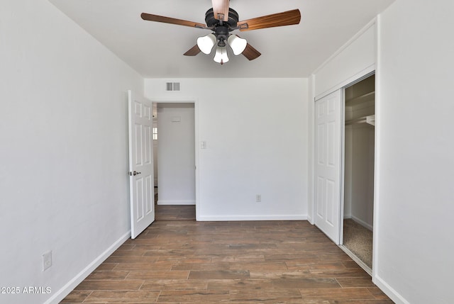 unfurnished bedroom with baseboards, a closet, visible vents, and wood finished floors