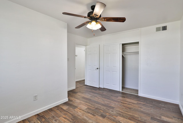 unfurnished bedroom featuring ceiling fan, dark wood-style flooring, visible vents, baseboards, and a closet