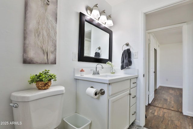 bathroom with baseboards, vanity, toilet, and wood finished floors