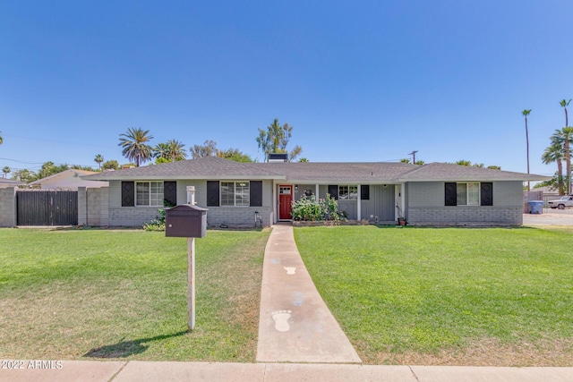 ranch-style house featuring a front yard, fence, and brick siding