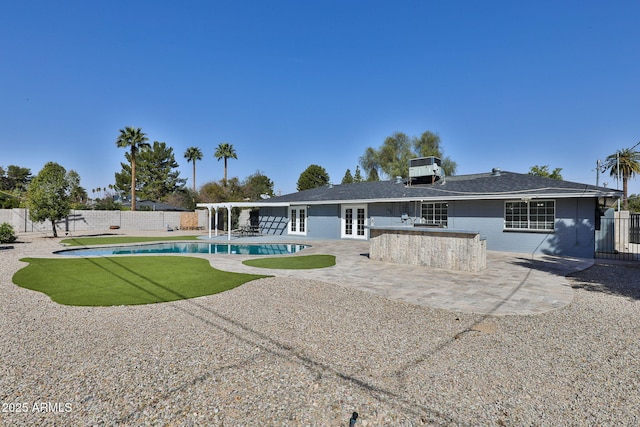 rear view of property with a fenced backyard, outdoor dry bar, a patio, and french doors