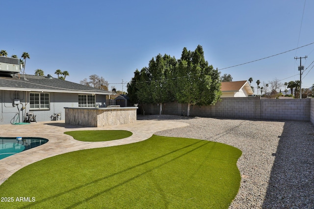 view of yard featuring a fenced backyard, outdoor dry bar, exterior kitchen, and a patio