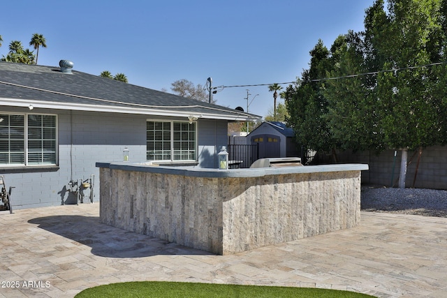 view of patio with an outbuilding, fence, and a storage unit