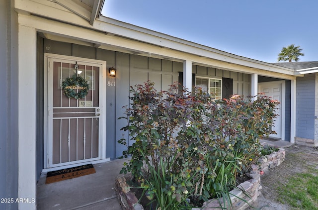 doorway to property with board and batten siding, brick siding, and a porch