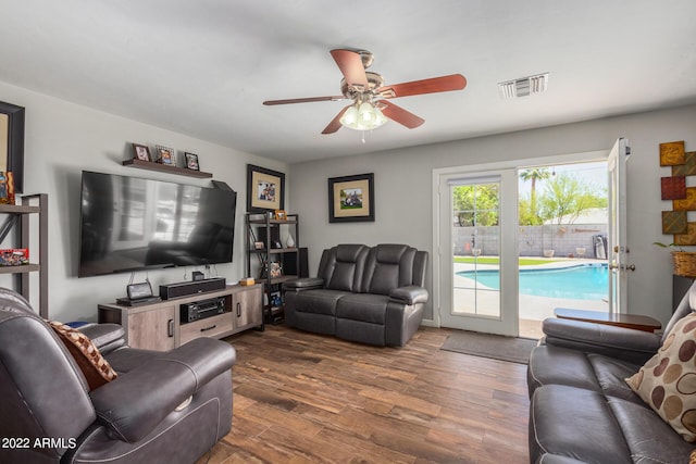 living area featuring dark wood-style flooring, visible vents, and a ceiling fan