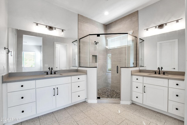 bathroom with a stall shower, two vanities, and a sink