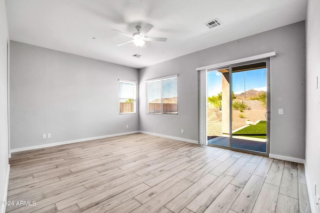 spare room featuring a wealth of natural light, light wood-type flooring, visible vents, and baseboards