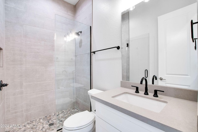 bathroom with tiled shower, vanity, and toilet