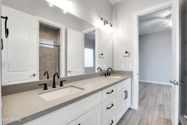 full bath featuring double vanity, wood finished floors, a sink, and baseboards