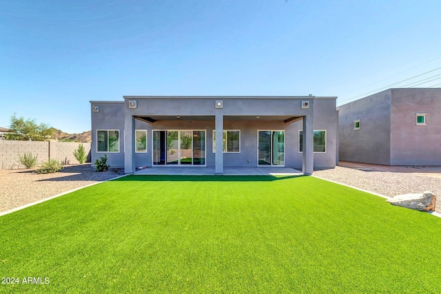 rear view of house featuring a yard, fence, a patio, and stucco siding