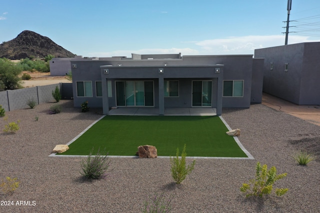 rear view of property with a mountain view, a patio area, and a yard