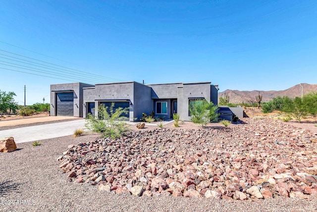 view of front of house with driveway, an attached garage, a mountain view, and stucco siding