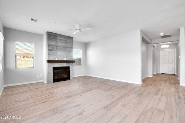 unfurnished living room featuring baseboards, a fireplace, visible vents, and light wood-style floors