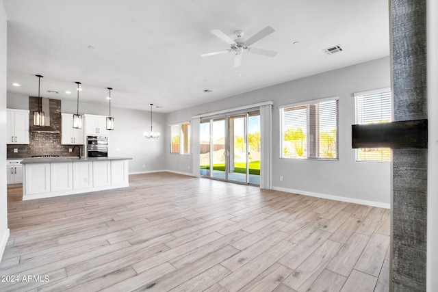 kitchen featuring visible vents, decorative backsplash, wall chimney exhaust hood, open floor plan, and a sink