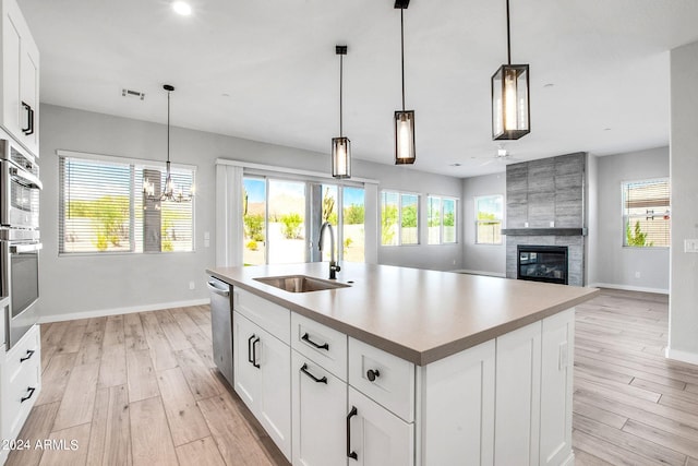 kitchen with a sink, visible vents, appliances with stainless steel finishes, light wood finished floors, and a tiled fireplace