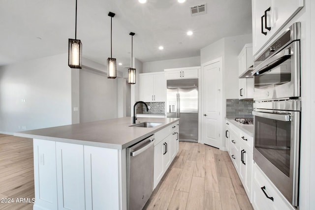 kitchen featuring light wood finished floors, visible vents, appliances with stainless steel finishes, a kitchen island with sink, and a sink