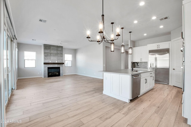 kitchen featuring appliances with stainless steel finishes, a fireplace, backsplash, and visible vents