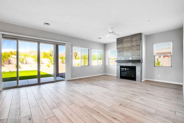 unfurnished living room with a large fireplace, light wood finished floors, visible vents, and a healthy amount of sunlight