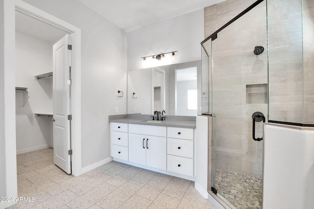 bathroom featuring a stall shower, vanity, baseboards, and a spacious closet