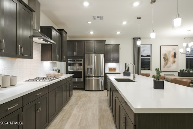 kitchen featuring a large island, sink, wall chimney range hood, and stainless steel appliances