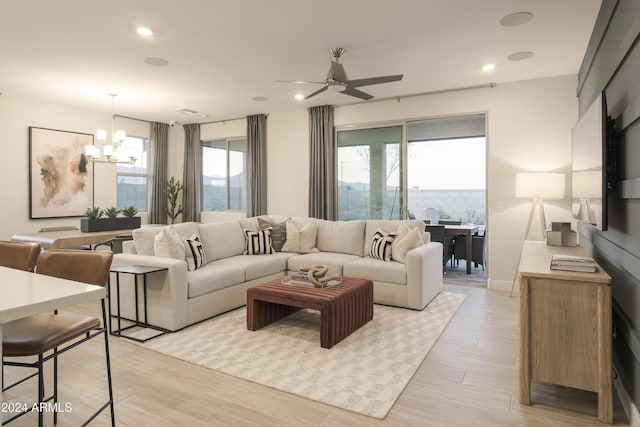 living room with ceiling fan with notable chandelier and light hardwood / wood-style floors