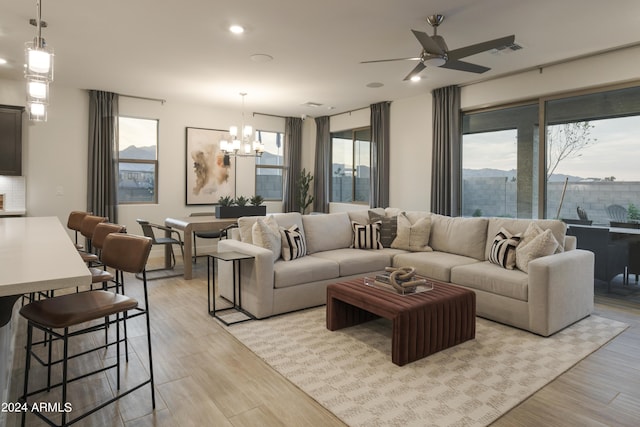 living room featuring a healthy amount of sunlight, light hardwood / wood-style floors, and ceiling fan with notable chandelier