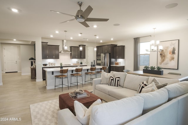 living room with ceiling fan with notable chandelier and light wood-type flooring