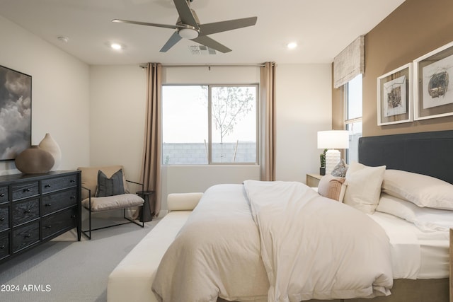 bedroom with ceiling fan, light carpet, and multiple windows