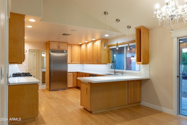 kitchen featuring kitchen peninsula, stainless steel appliances, light wood-type flooring, decorative light fixtures, and sink