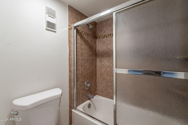 bathroom with toilet and combined bath / shower with glass door