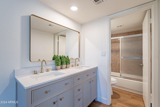 full bathroom featuring vanity, toilet, wood-type flooring, and shower / bath combination with glass door