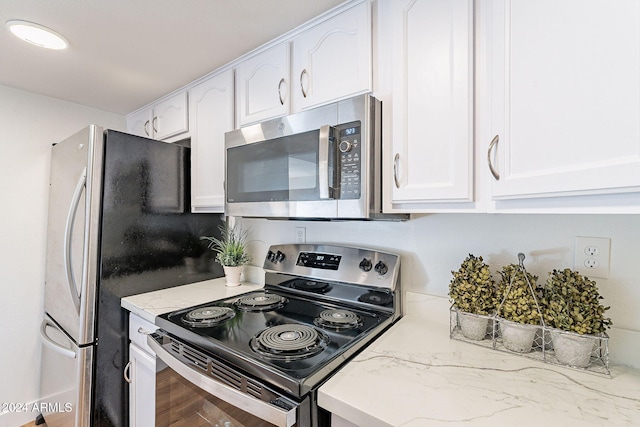 kitchen with light stone countertops, stainless steel appliances, and white cabinetry