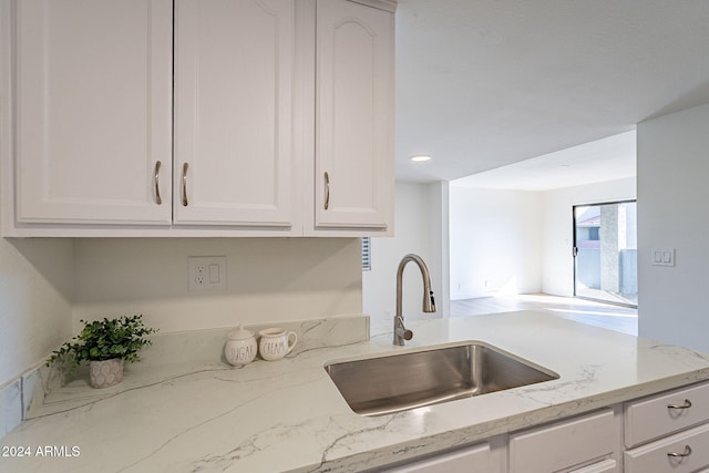 kitchen with light stone countertops, sink, and white cabinets