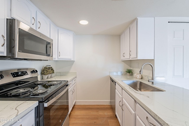 kitchen featuring white cabinets, sink, light hardwood / wood-style floors, stainless steel appliances, and light stone counters