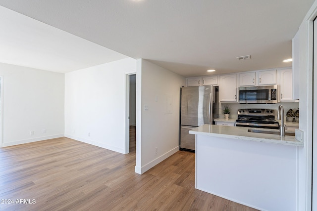 kitchen featuring sink, stainless steel appliances, light hardwood / wood-style flooring, kitchen peninsula, and white cabinets