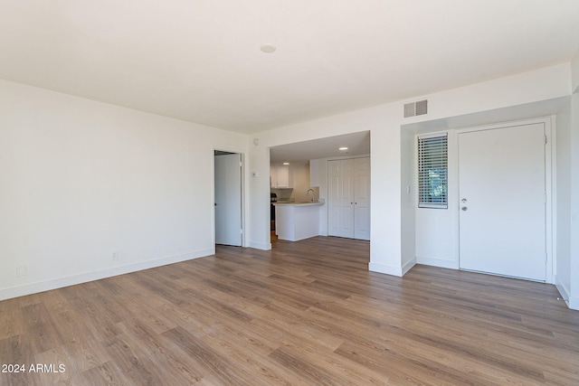 unfurnished living room featuring sink and light wood-type flooring