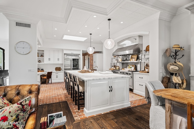 kitchen featuring light stone counters, high end stainless steel range oven, pendant lighting, a center island with sink, and white cabinetry