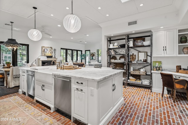 kitchen with ceiling fan, white cabinetry, an island with sink, and decorative light fixtures