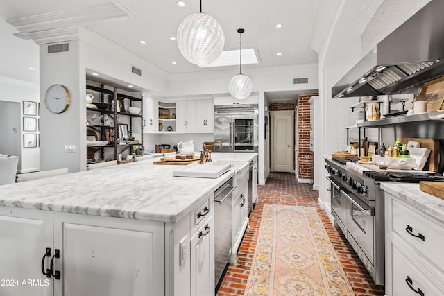 kitchen with white cabinetry, a center island, wall chimney exhaust hood, hanging light fixtures, and high end appliances