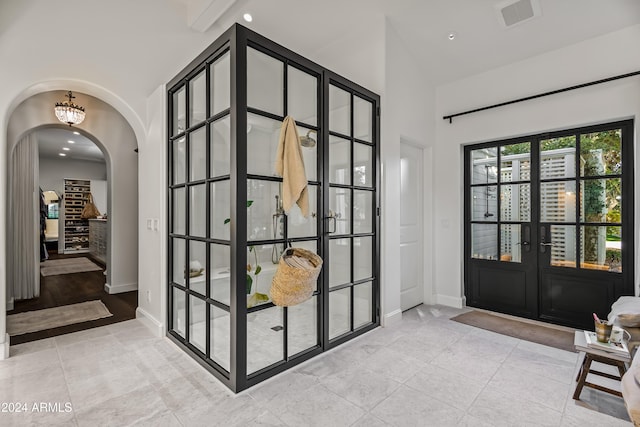 foyer with french doors, vaulted ceiling with beams, and light tile patterned floors