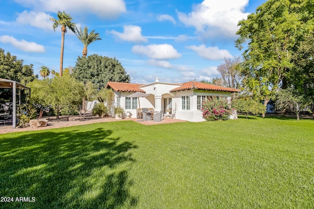 back of house with a lawn and a patio