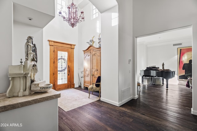 foyer entrance with a high ceiling, dark hardwood / wood-style floors, and a notable chandelier