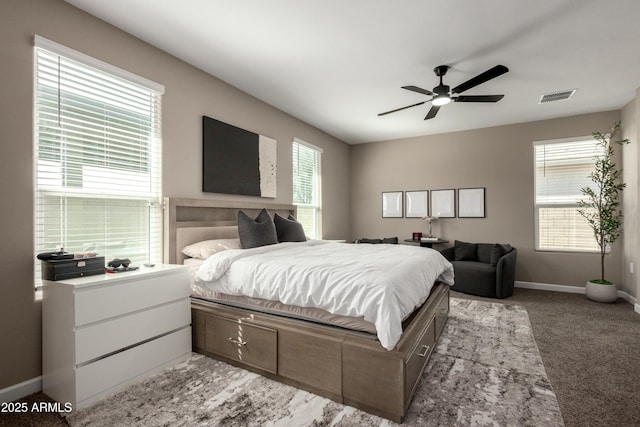 carpeted bedroom with visible vents, baseboards, and a ceiling fan