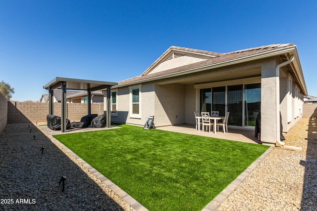 rear view of house with stucco siding, a patio, a lawn, and a fenced backyard