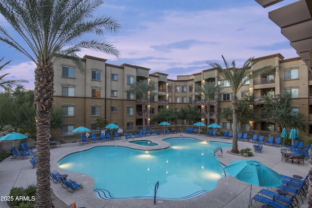 pool at dusk featuring a community hot tub and a patio area