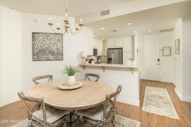 dining space with a chandelier and light wood-type flooring