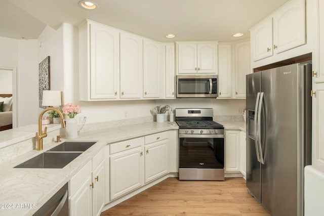 kitchen featuring sink, white cabinets, light hardwood / wood-style flooring, and appliances with stainless steel finishes